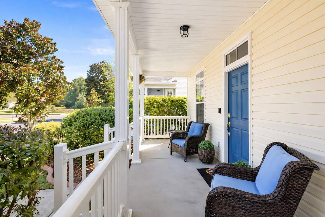 Sunny front porch with wicker chairs and the blue front door